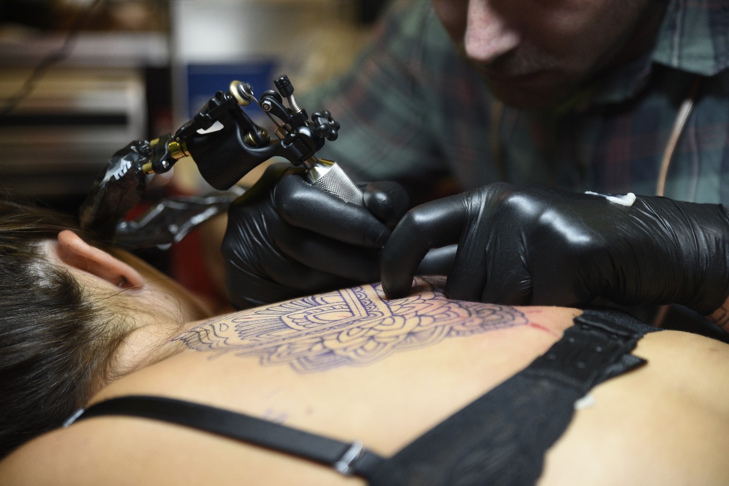 Close up of tattoo artist working with needle on skin
